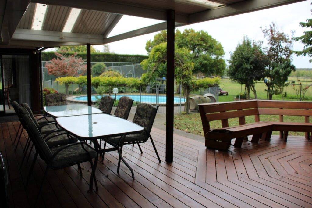 Covered deck with outdoor dining, overlooking the pool