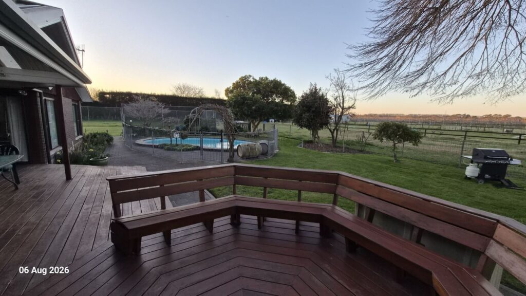 Deck bench seating looking out over the pool and paddocks at dusk